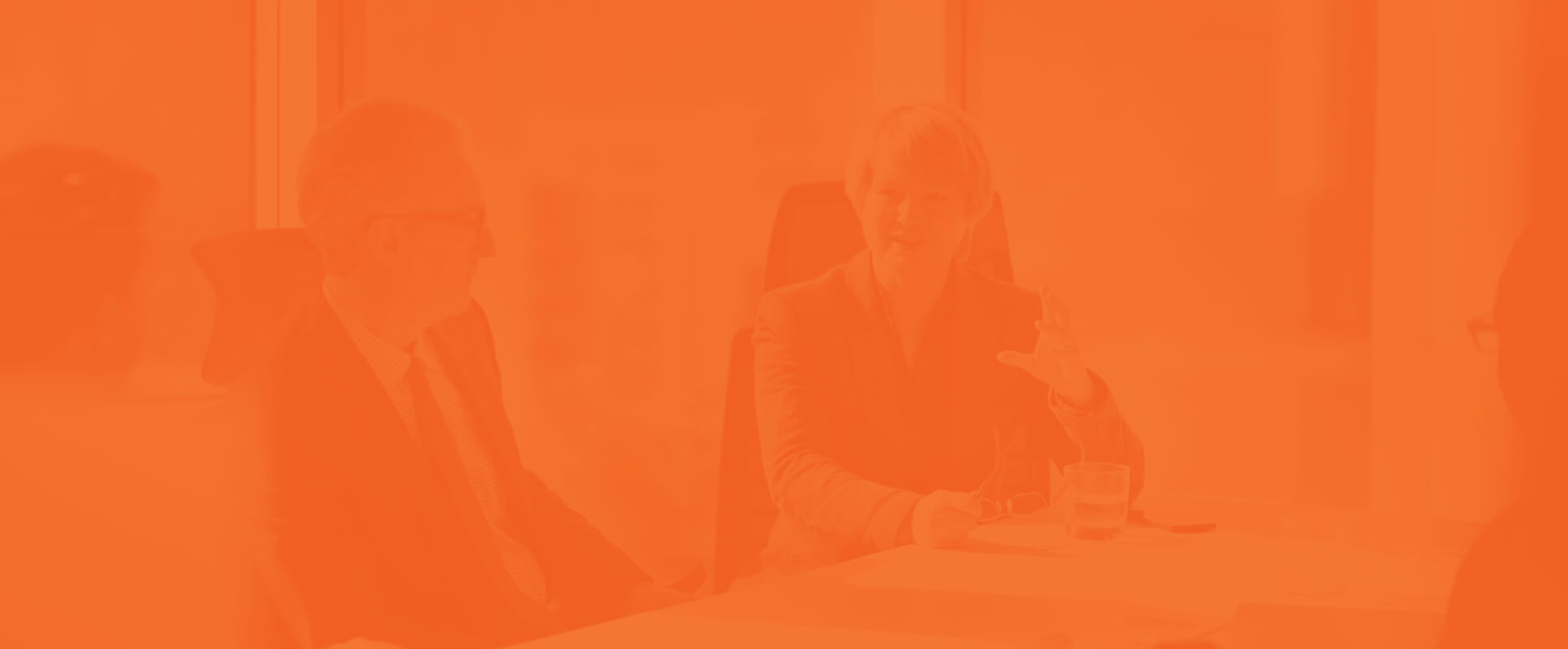 A group of office workers sat at a desk having a discussion